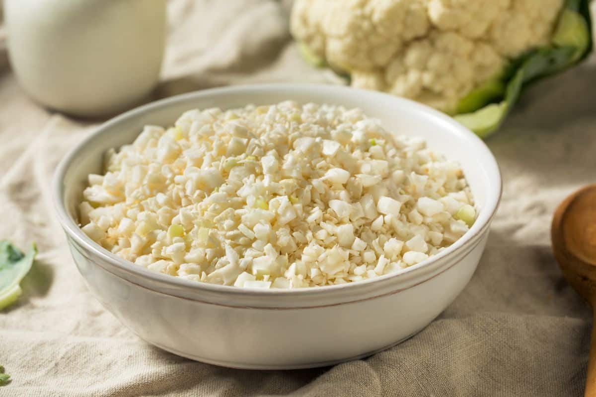 raw cauliflower rice in a white bowl.