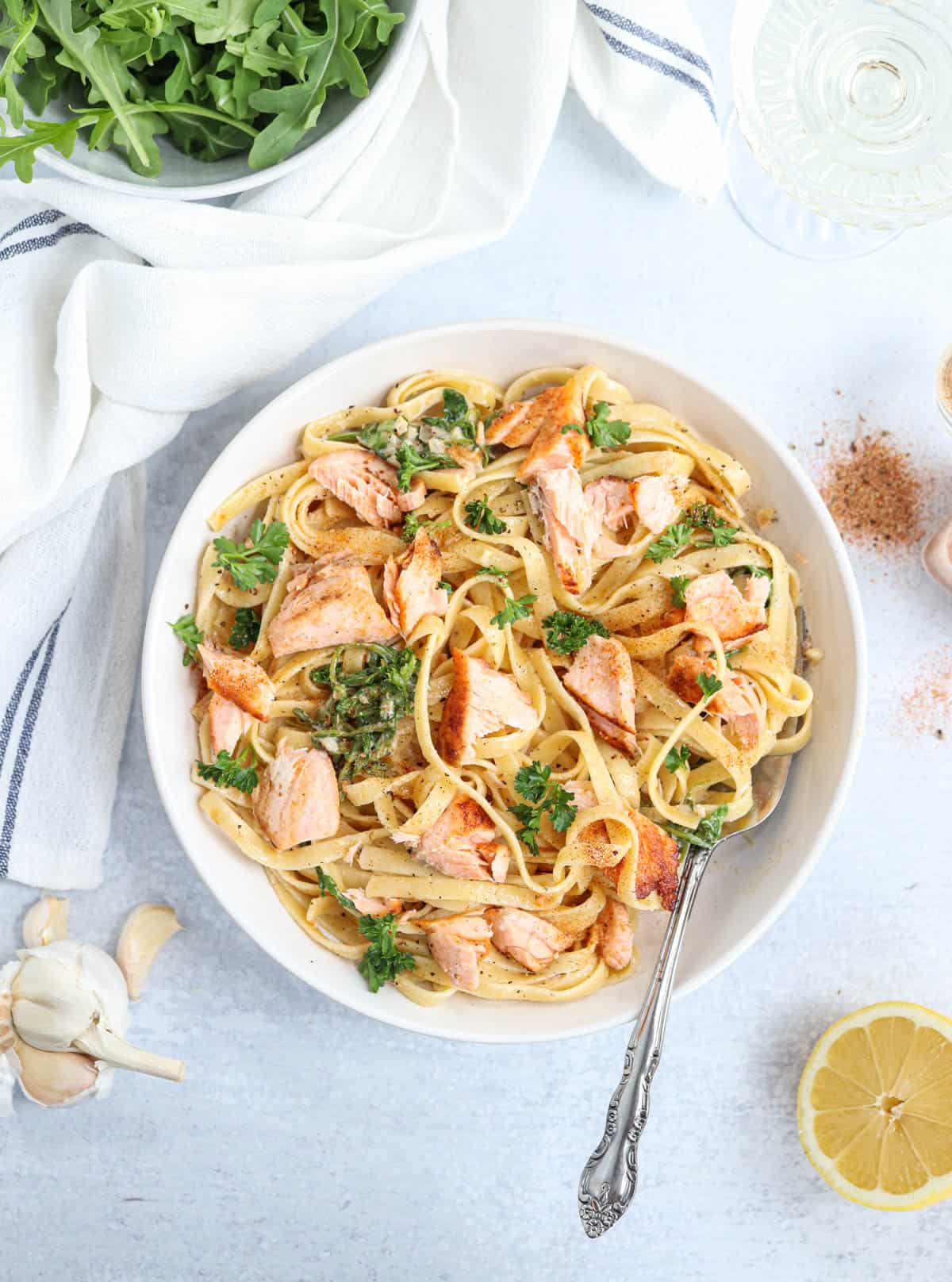 fettucine pasta with salmon and greens in a white bowl. 