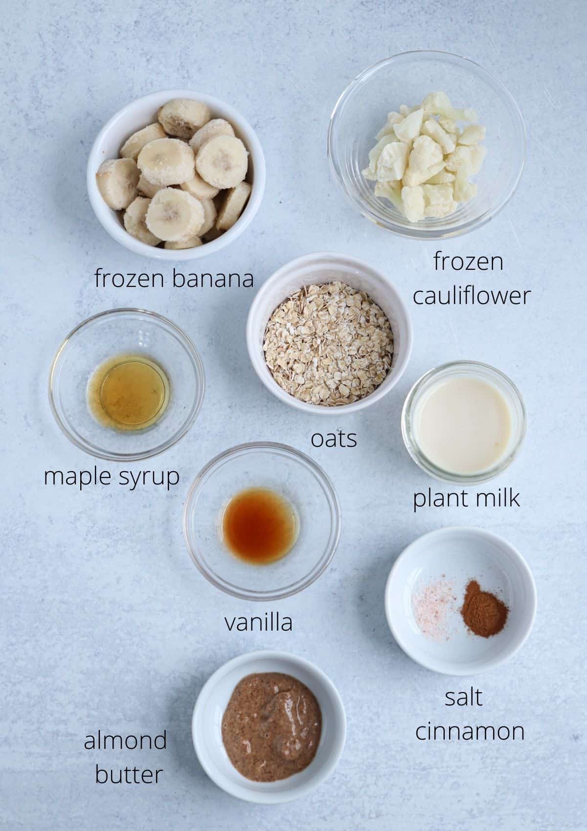 ingredients for making an oatmeal smoothie bowl in small bowls with captions.