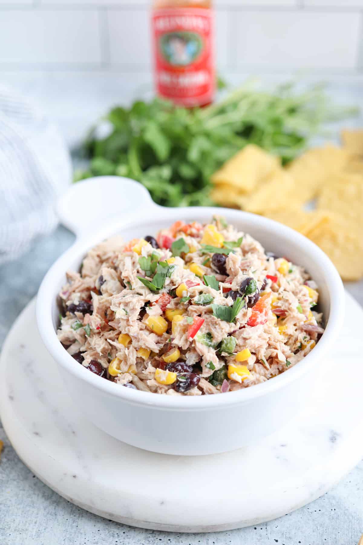 tuna salad with black beans, sweet corn, red peppers and fresh cilantro in a white bowl. 