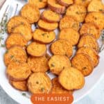 A white platter holds neatly arranged roasted sweet potato slices garnished with herbs, with a fork on the side. Text on the image reads, The Easiest Sliced Roasted Sweet Potatoes.