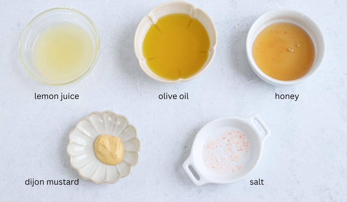 Five small dishes with labeled ingredients—lemon juice, olive oil, honey, Dijon mustard, and salt—arranged on a light surface, perfect for preparing a flavorful chicken potato broccoli casserole.